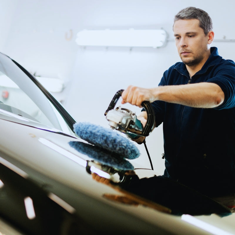 homme utilisant un appareil pour lustrer une voiture